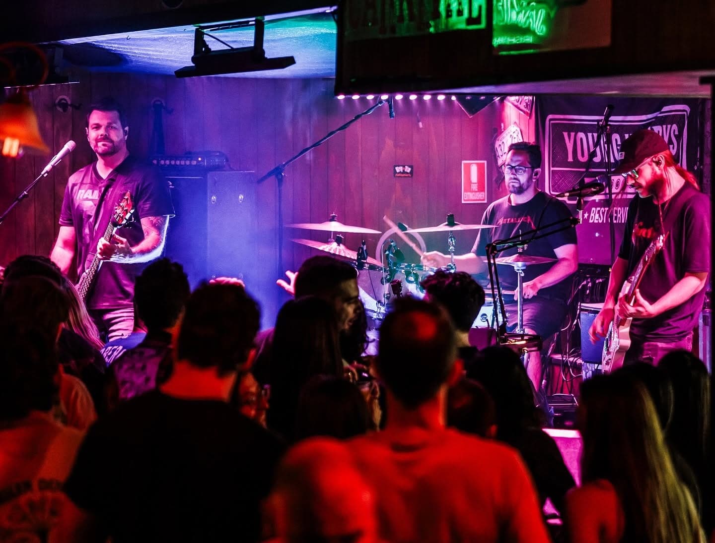 Crowd packed in front of the band under pink and blue lights