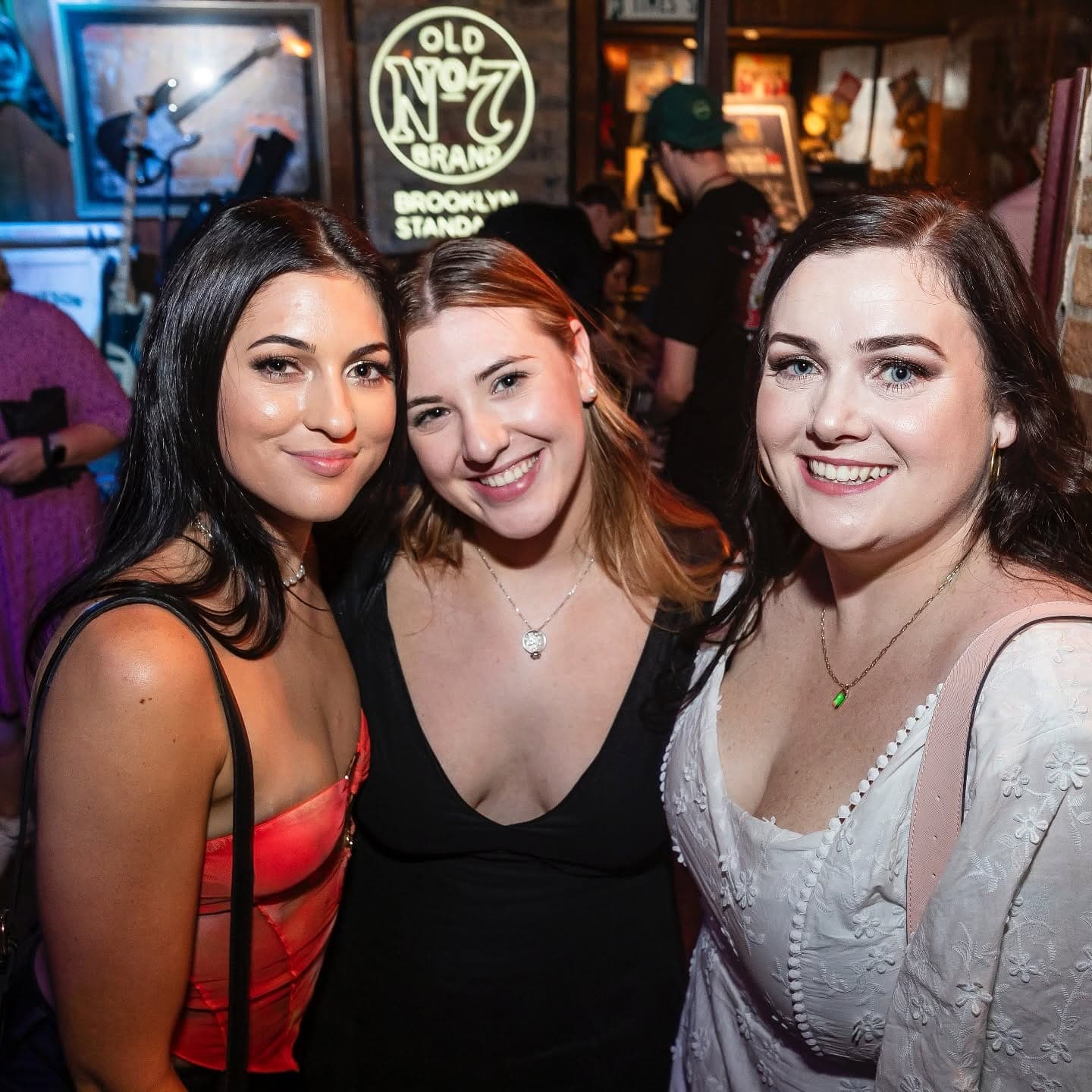 Three friends under the Old No. 7 neon
