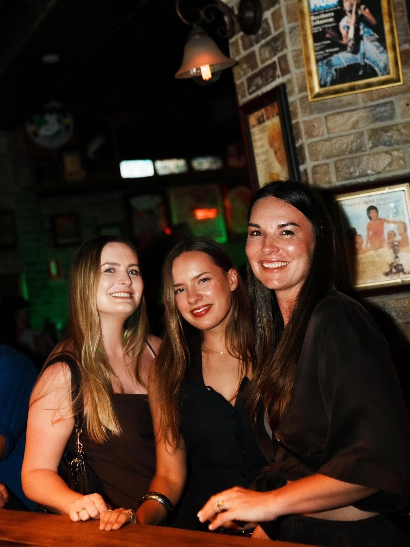 Three friends smiling beside the brick wall