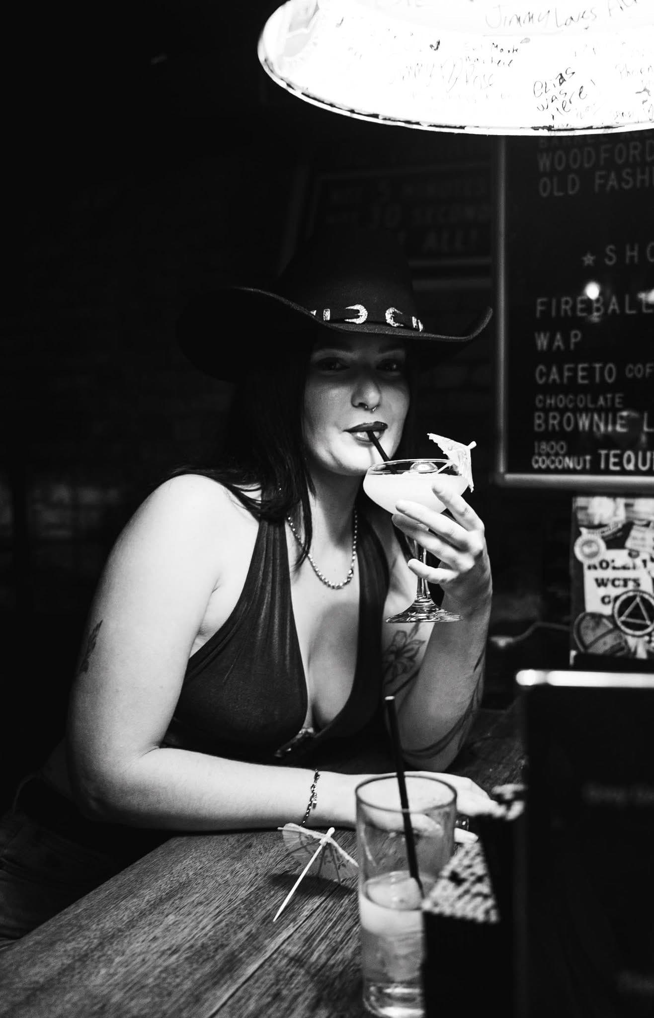 Woman in a cowboy hat sipping a cocktail